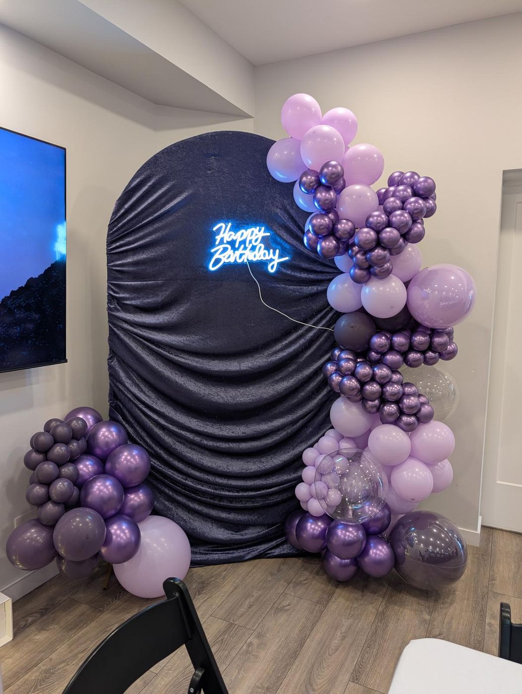 Navy velvet arch backdrop with purple balloon garland and neon sign